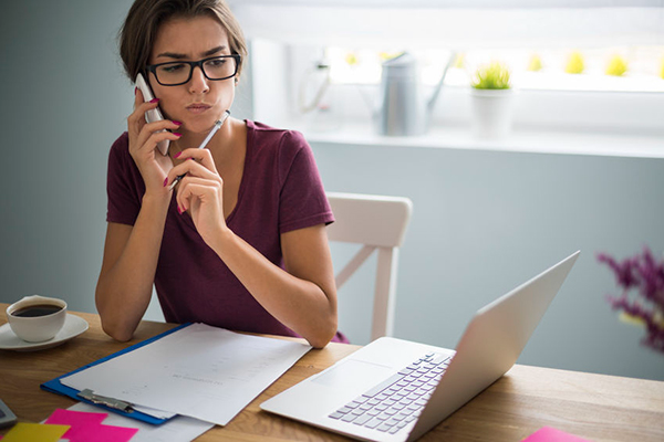 person on phone and computer filling out papers